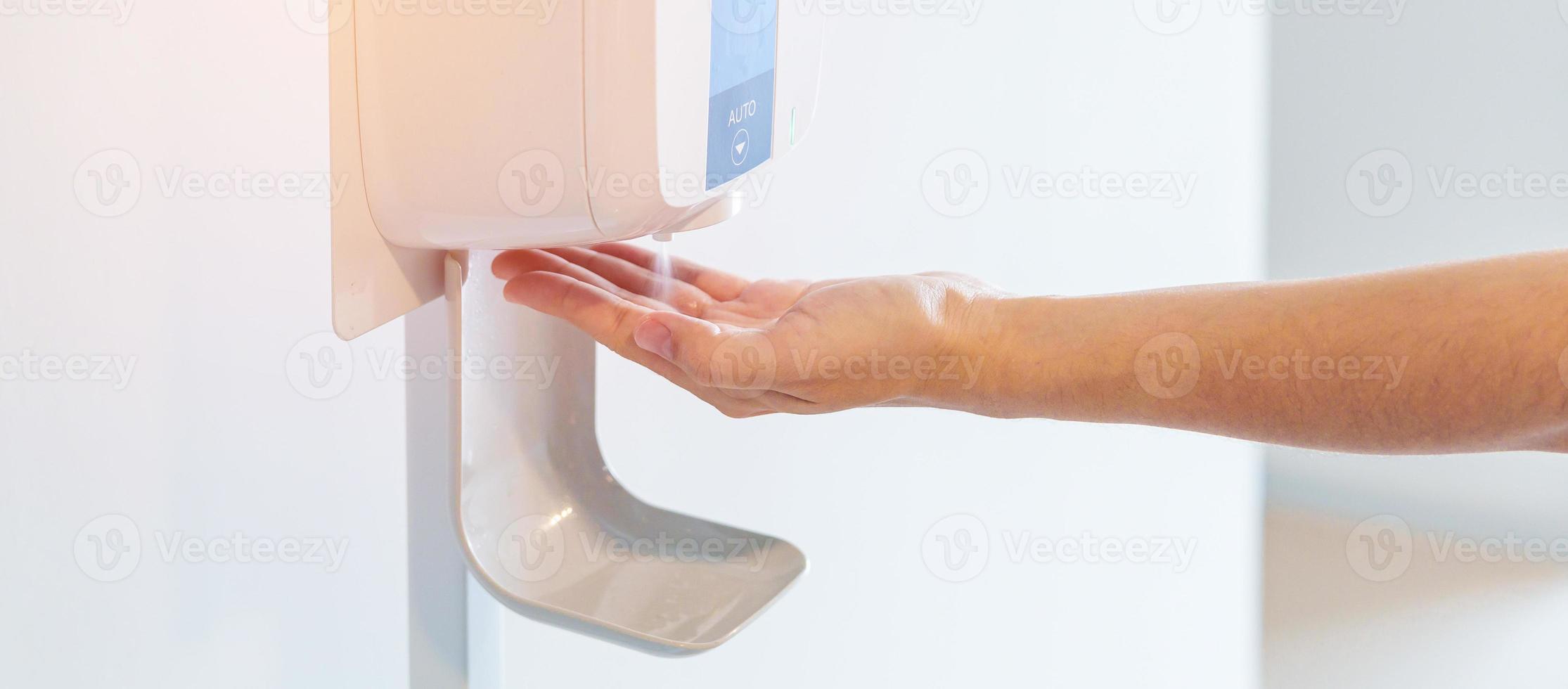 hand spray by automatic sanitizer dispenser in office or apartment. Contactless and Personal hygiene concept photo