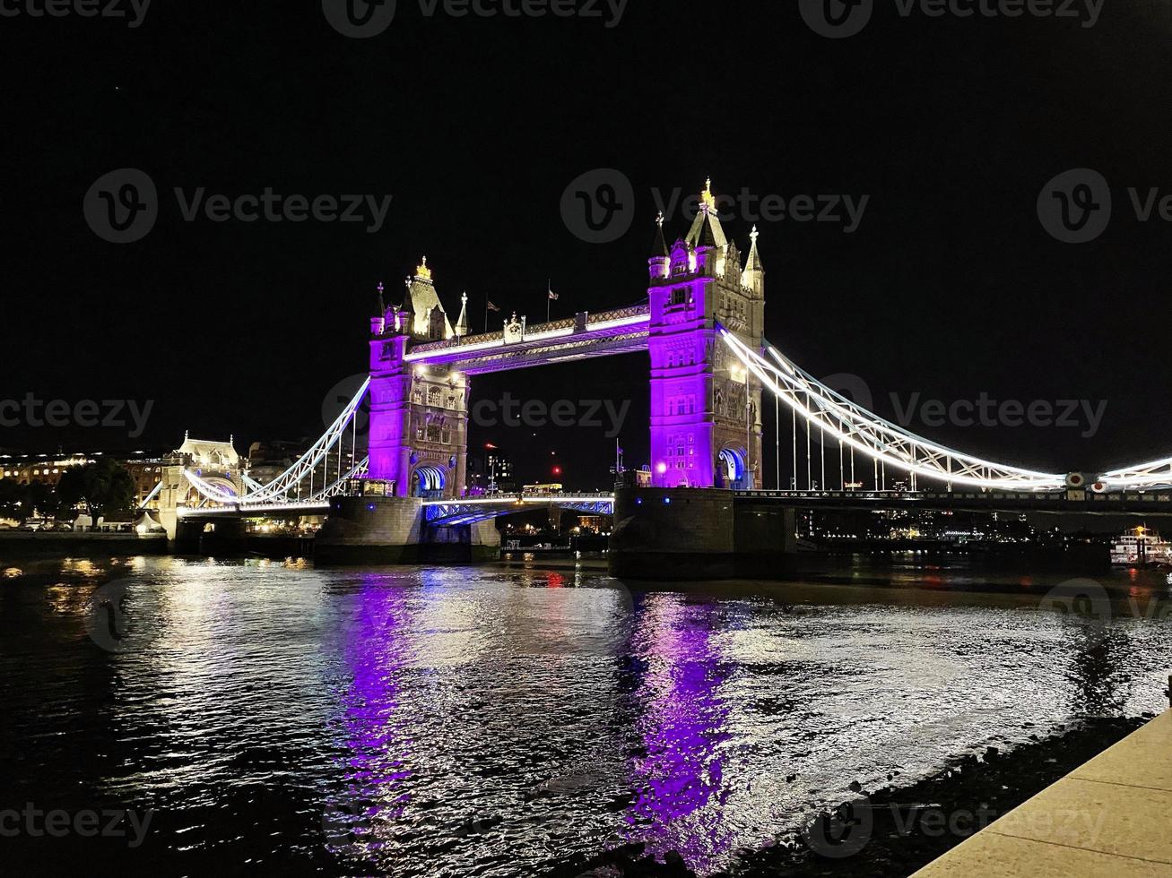 una vista del puente de la torre en londres en la noche iluminada en púrpura foto