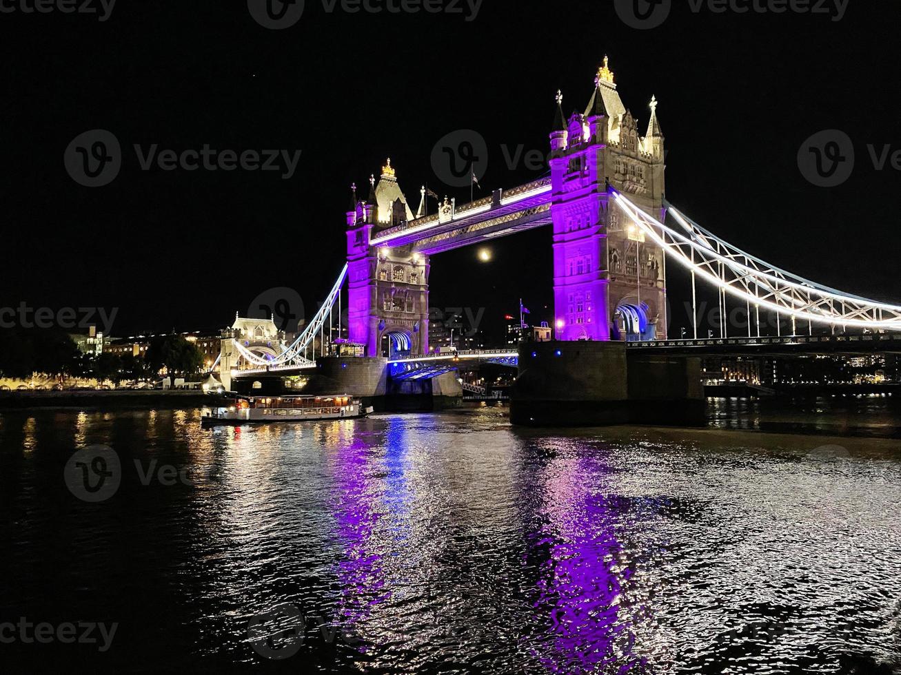 A view of Tower Bridge in London at night lit up in purple photo