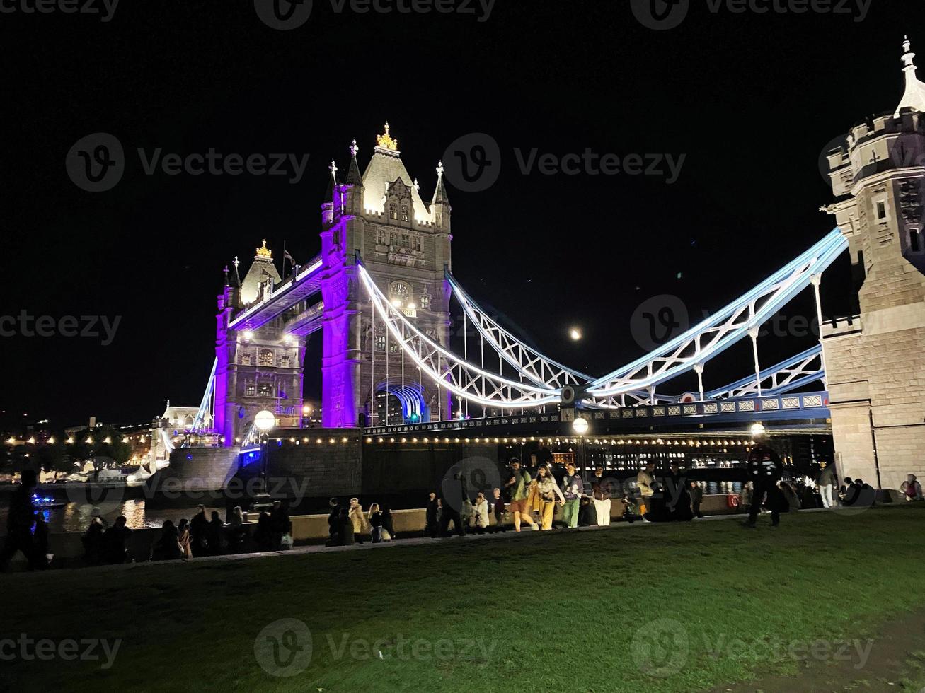 A view of Tower Bridge in London at night lit up in purple photo