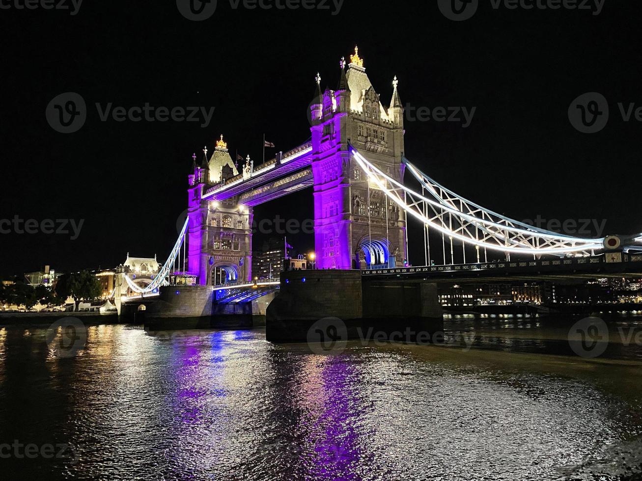 A view of Tower Bridge in London at night lit up in purple photo
