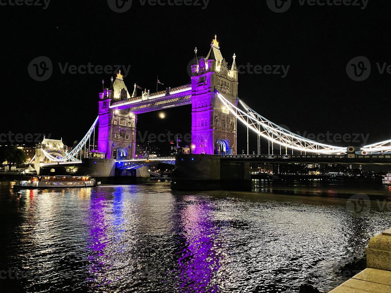 A view of Tower Bridge in London at night lit up in purple photo