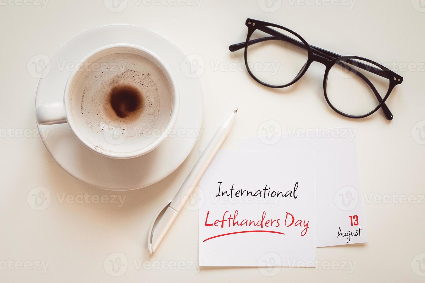 International lefthanders day greeting on August 13, desktop flat lay with coffee cup, pen, eyeglasses and paper note photo