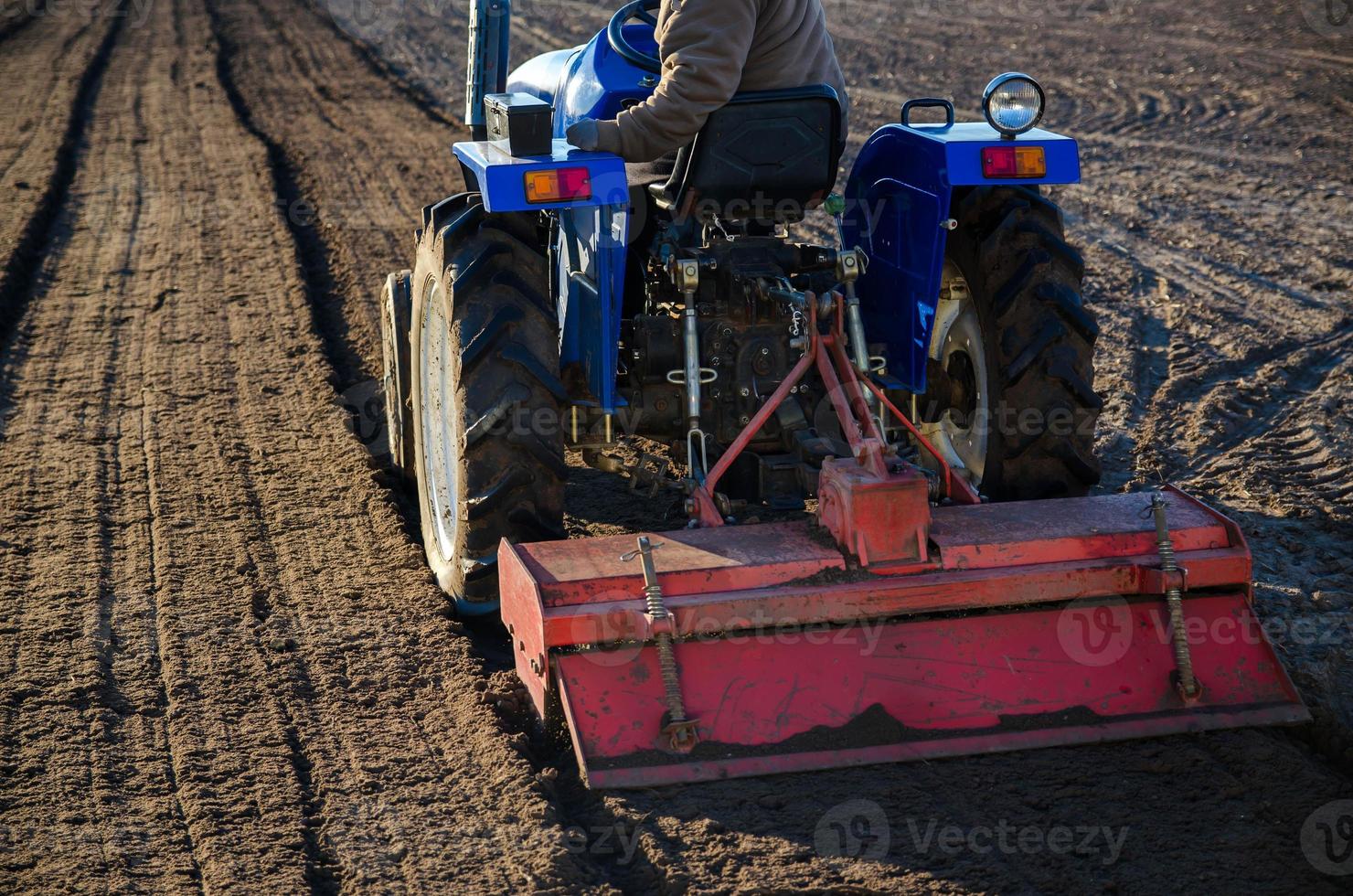 A farmer on a tractor cultivates a farm field. Softening the soil and preparing for cutting rows for the next sowing season in the spring. Land cultivation. Farm business. Work in agricultural photo