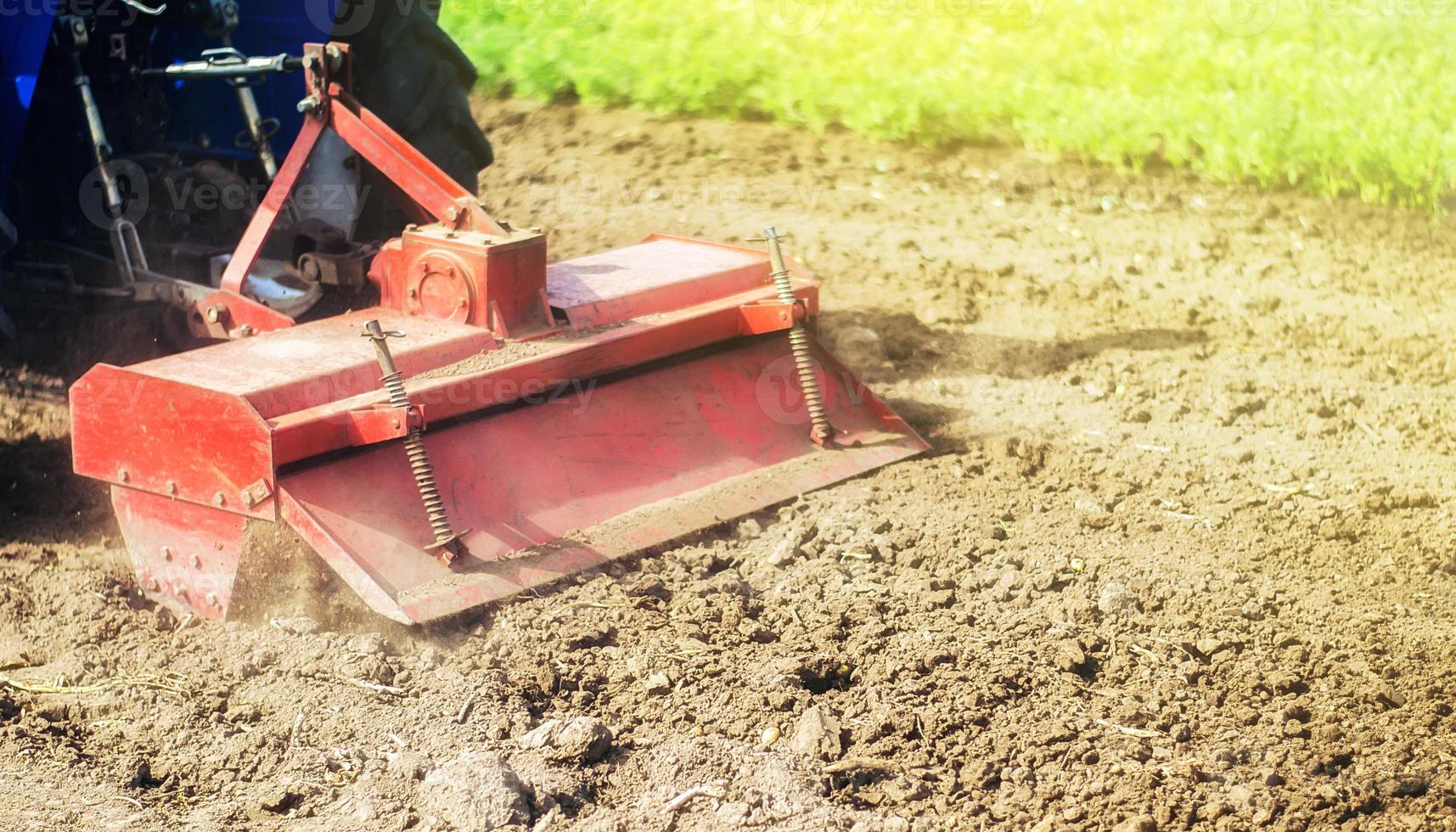 Tractor with milling machine loosens, grinds and mixes ground. Field preparation for new crop planting. Cultivation equipment. Grinding and loosening soil, removing plants and roots from past harvest. photo