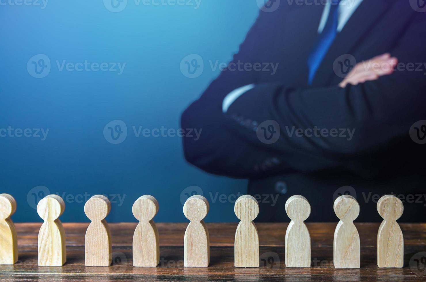 A businessman in the background examines a row of candidates figurine. Hiring new employees and recruiting staff. Society and social groups. Public relations. Human resources. Personnel management. photo