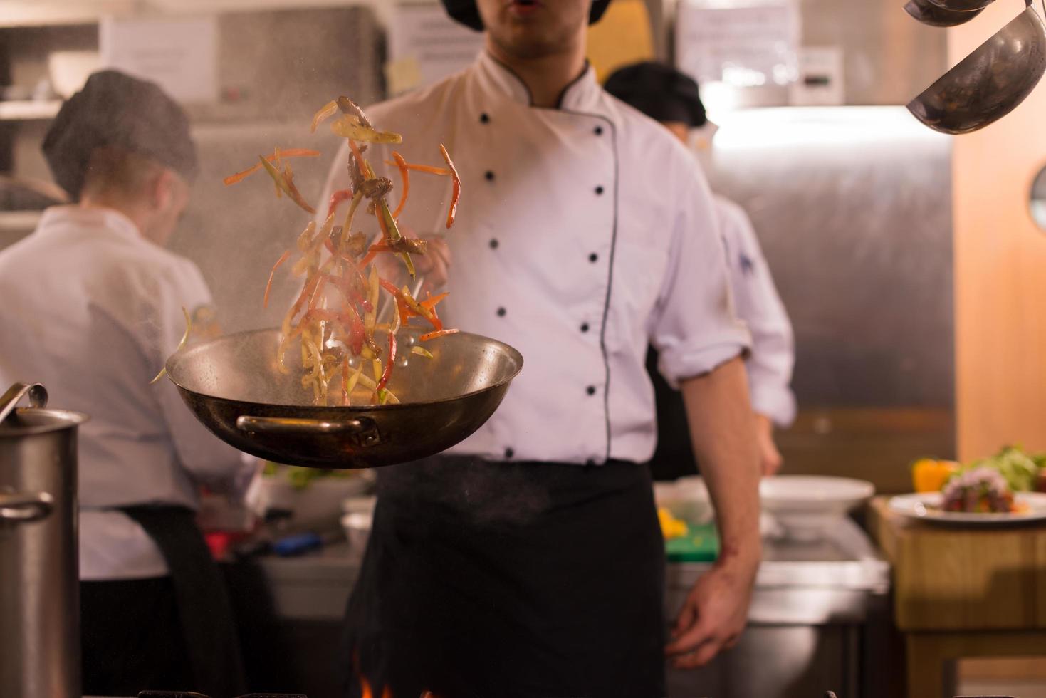 chef volteando verduras en wok foto