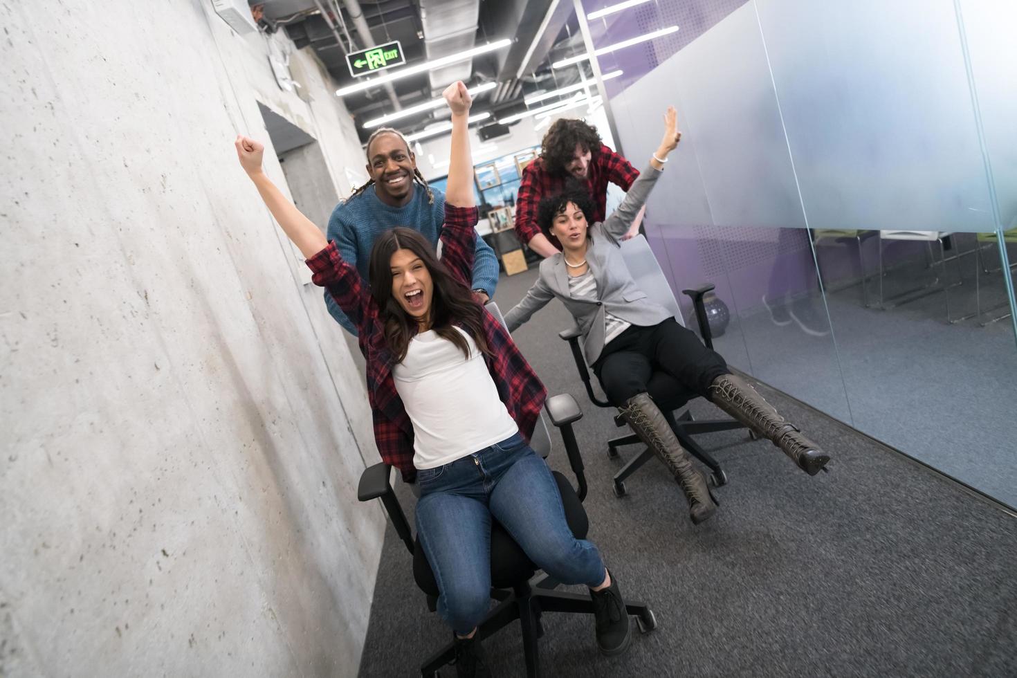 equipo de negocios multiétnico corriendo en sillas de oficina foto