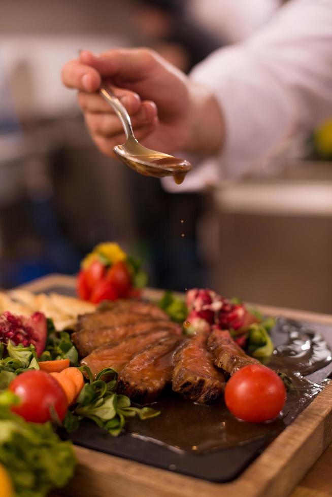 Chef finishing steak meat plate photo