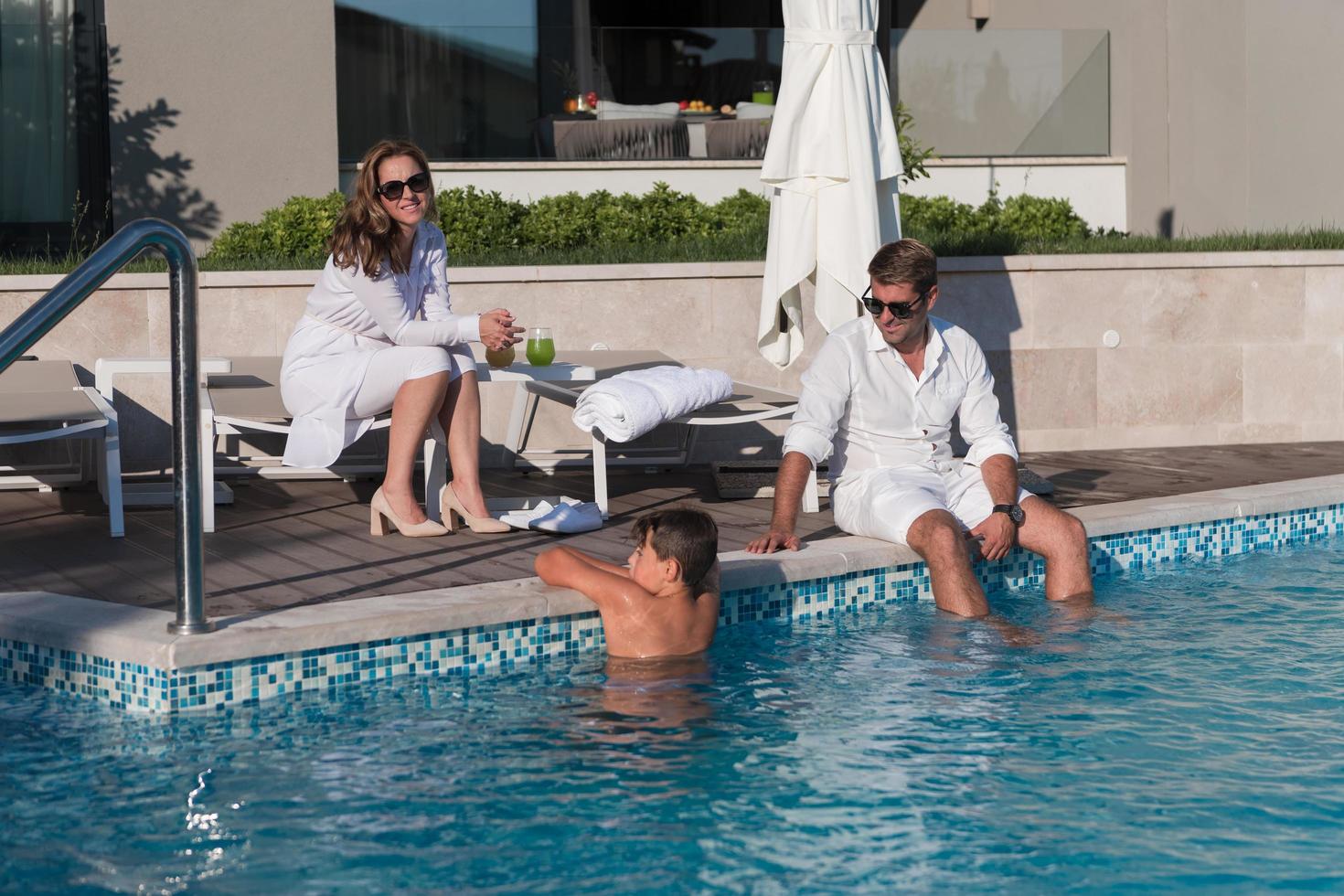 familia feliz disfruta de vacaciones en una casa de lujo con piscina. la pareja mayor pasa tiempo con su hijo durante las vacaciones. enfoque selectivo foto