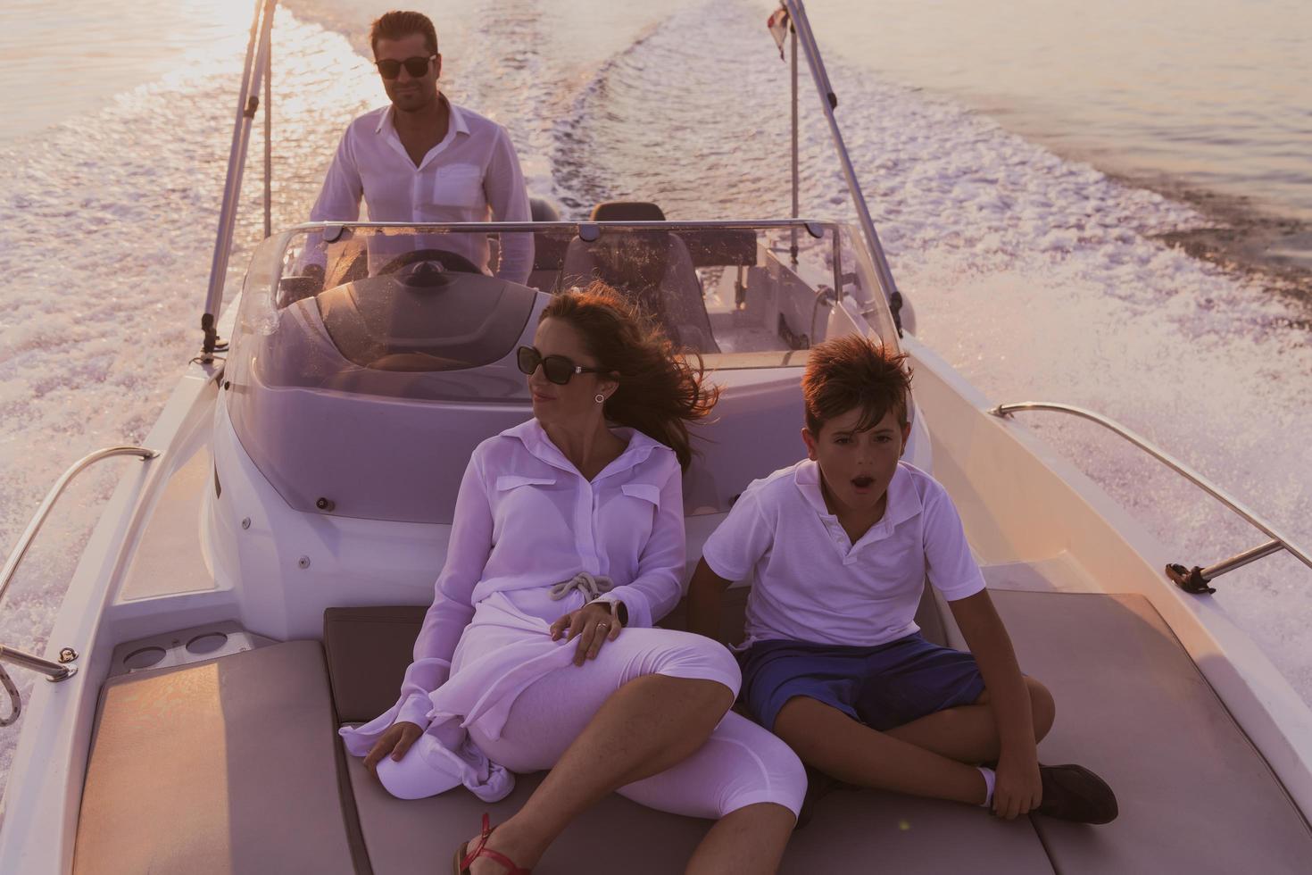 A senior couple in casual outfits with their son enjoy while riding a boat at sea at sunset. The concept of a happy family. Selective focus photo