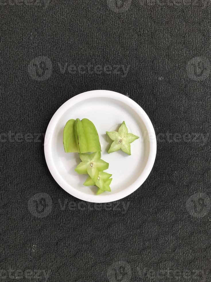 Green star fruit slices on a pink plastic plate photo