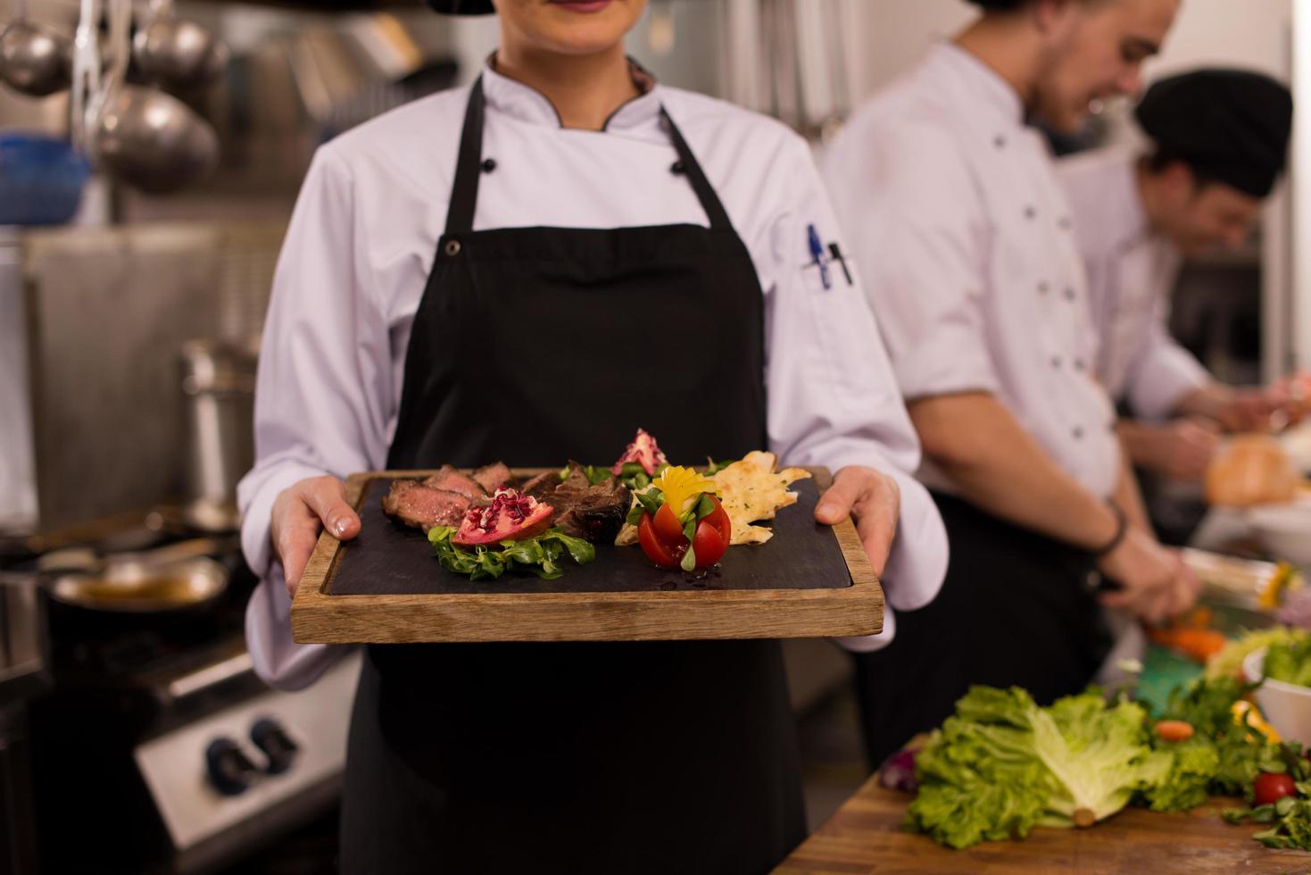 female Chef holding beef steak plate photo