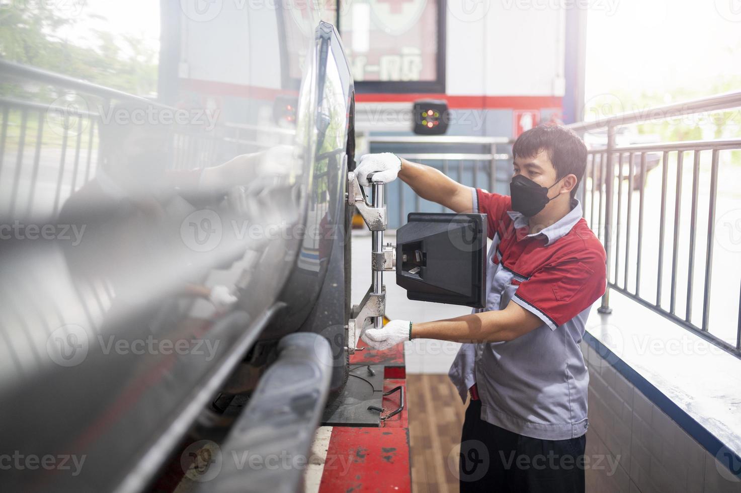 Professional mechanic near wheel center, wheel alignment, mounted on each tire for driving center. Wheel alignment in the garage photo
