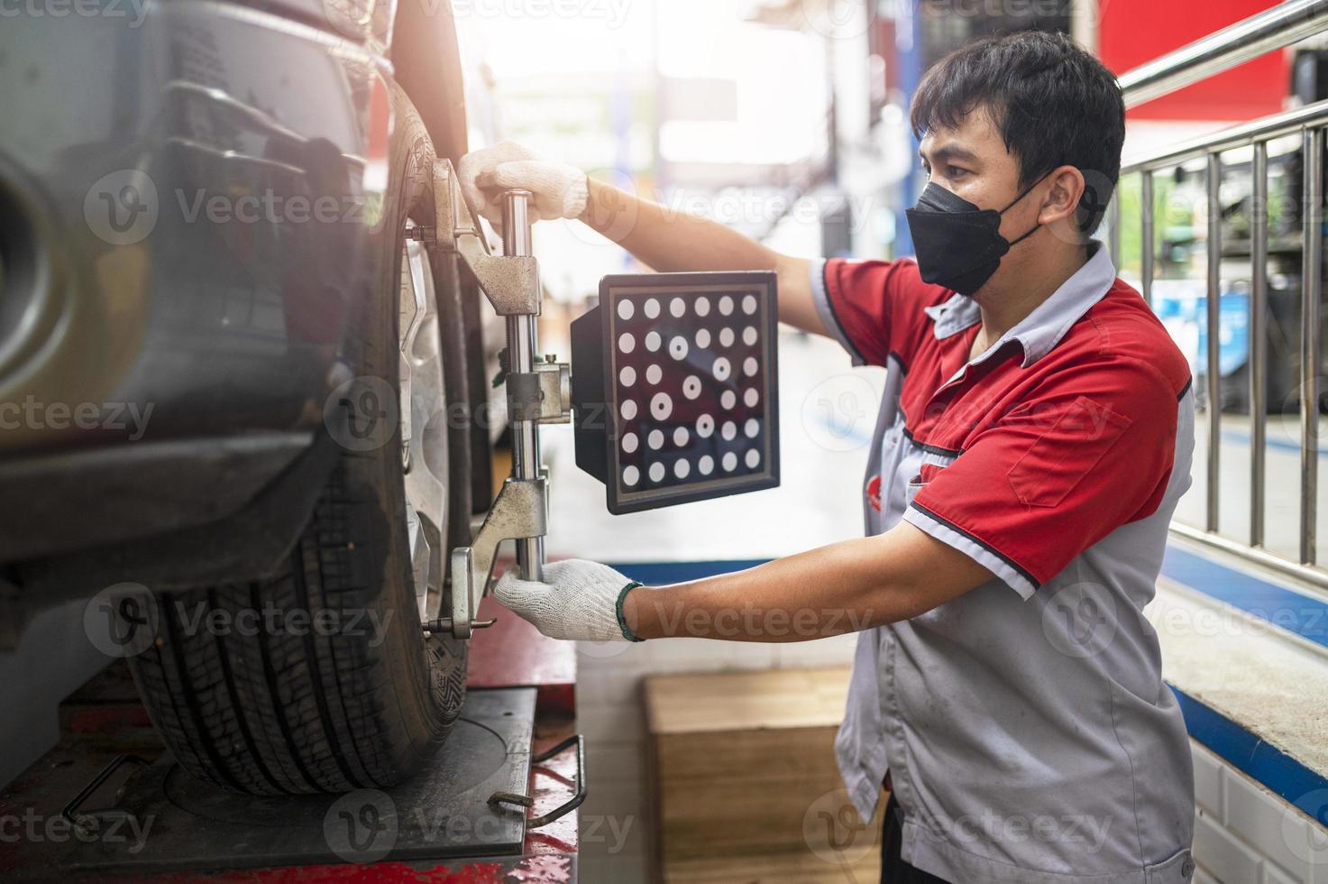 Professional mechanic near wheel center, wheel alignment, mounted on each tire for driving center. Wheel alignment in the garage photo