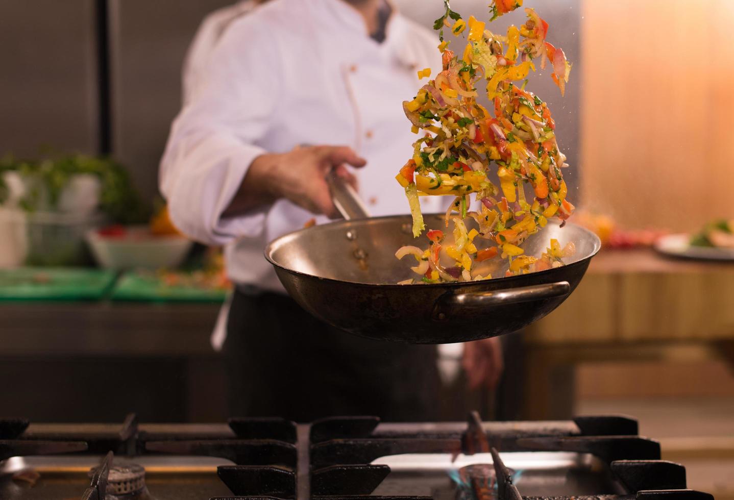 chef flipping vegetables in wok photo