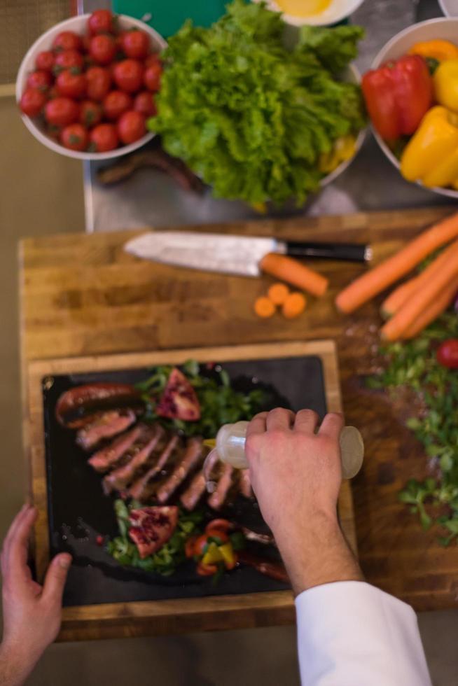 top view of Chef finishing steak meat plate photo