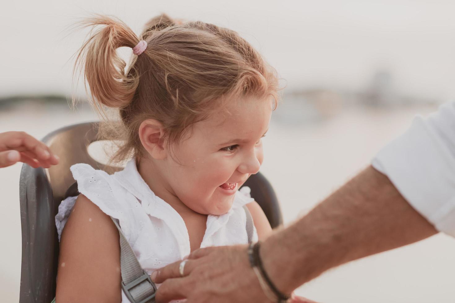 A portrait of a smiling little girl sitting in a bicycle seat. Selective focus photo