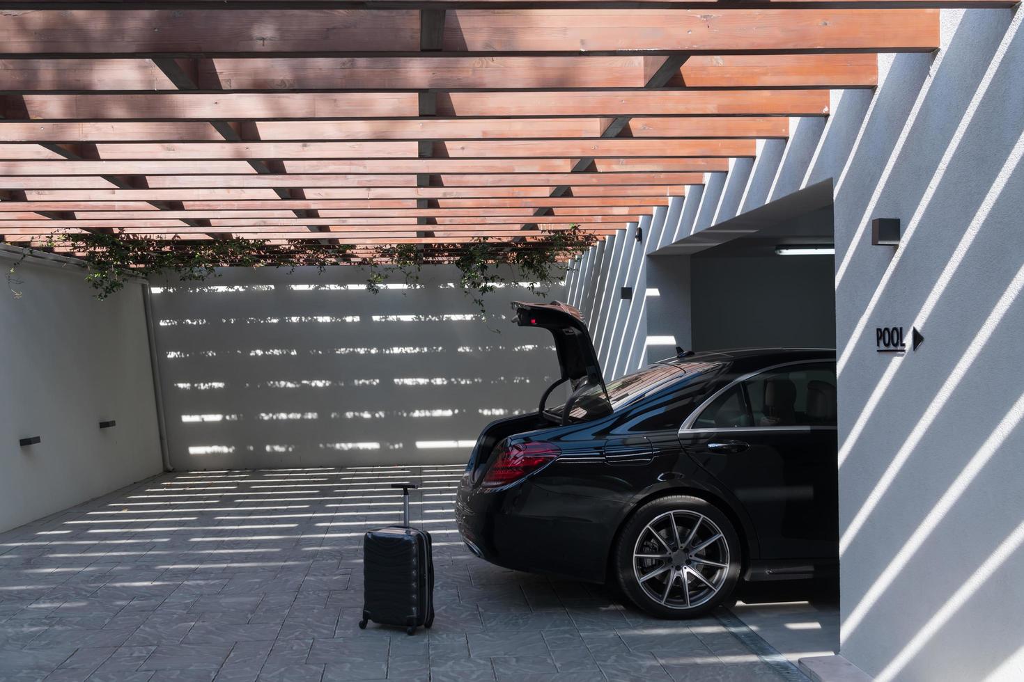 A photo of a suitcase standing next to a car in a luxury garage. Selective focus