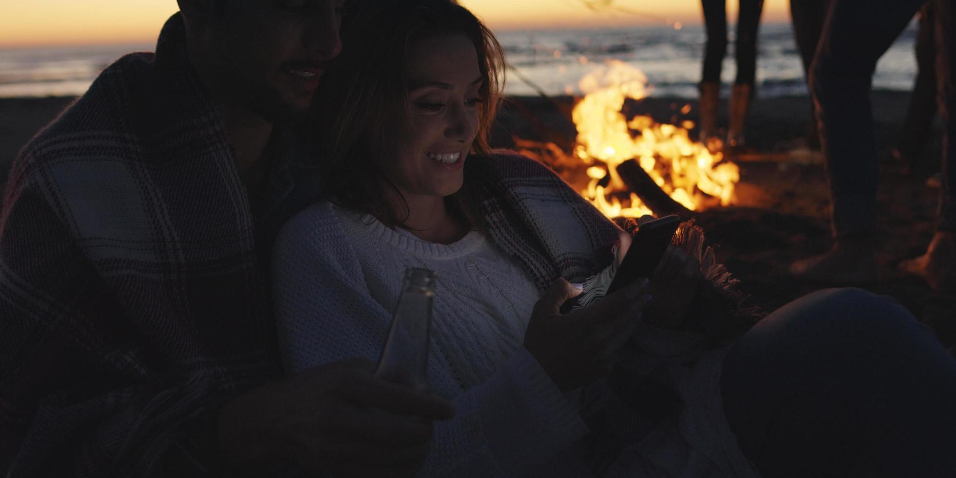 pareja disfrutando de la hoguera con amigos en la playa foto