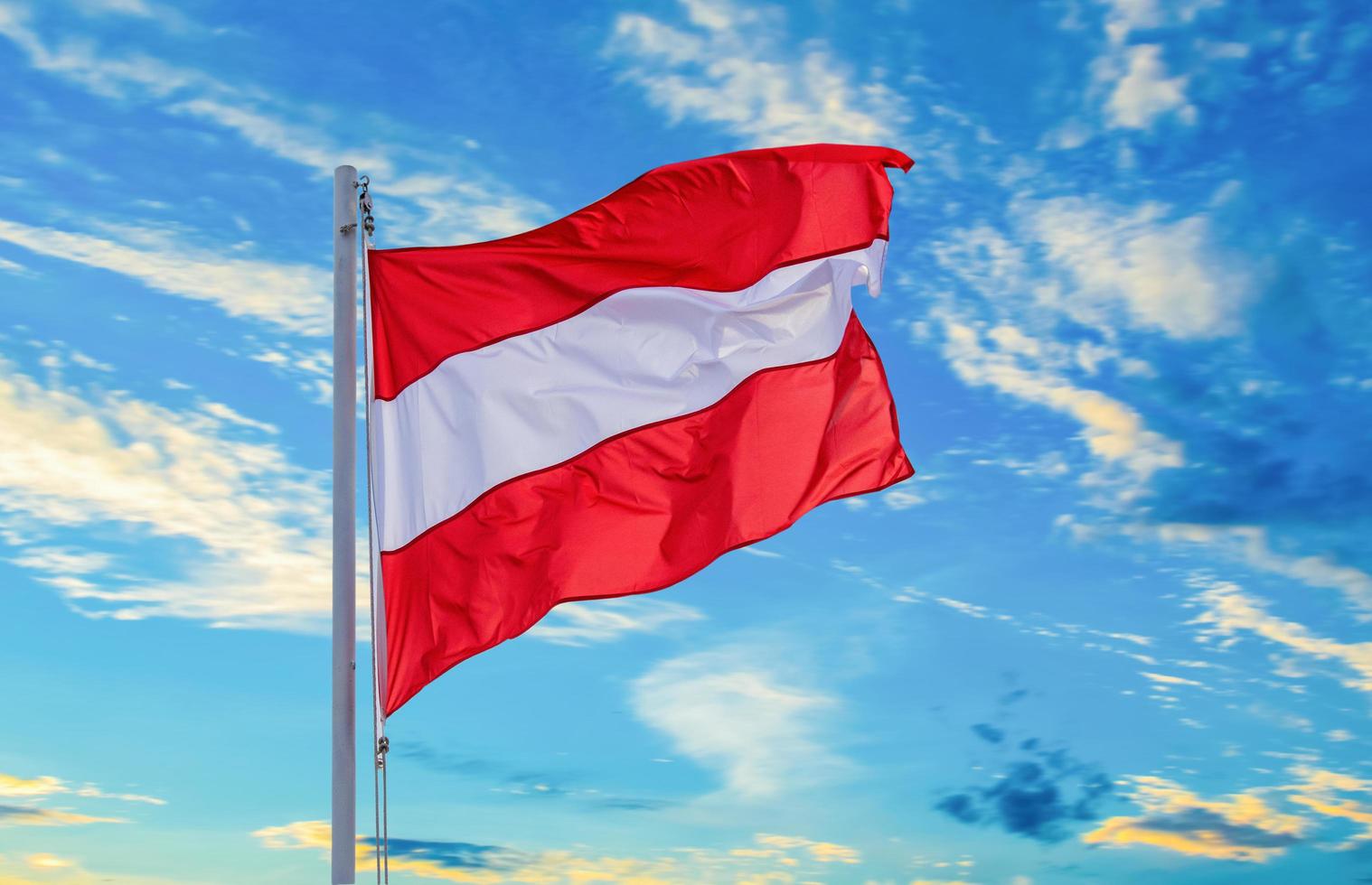 Austrian flag flutters on the pole above the beautiful blue sky. Austria's independence photo