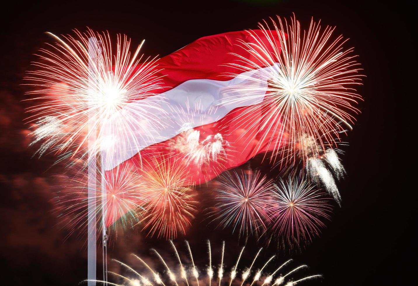 la bandera austriaca ondea en los postes sobre el cielo nocturno y los fuegos artificiales. independencia de austria foto