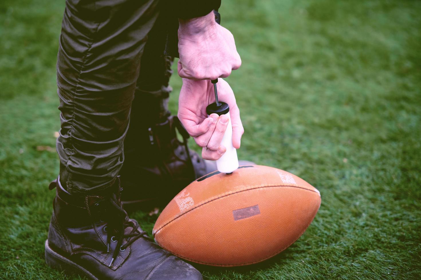 man pumping air into american football ball photo