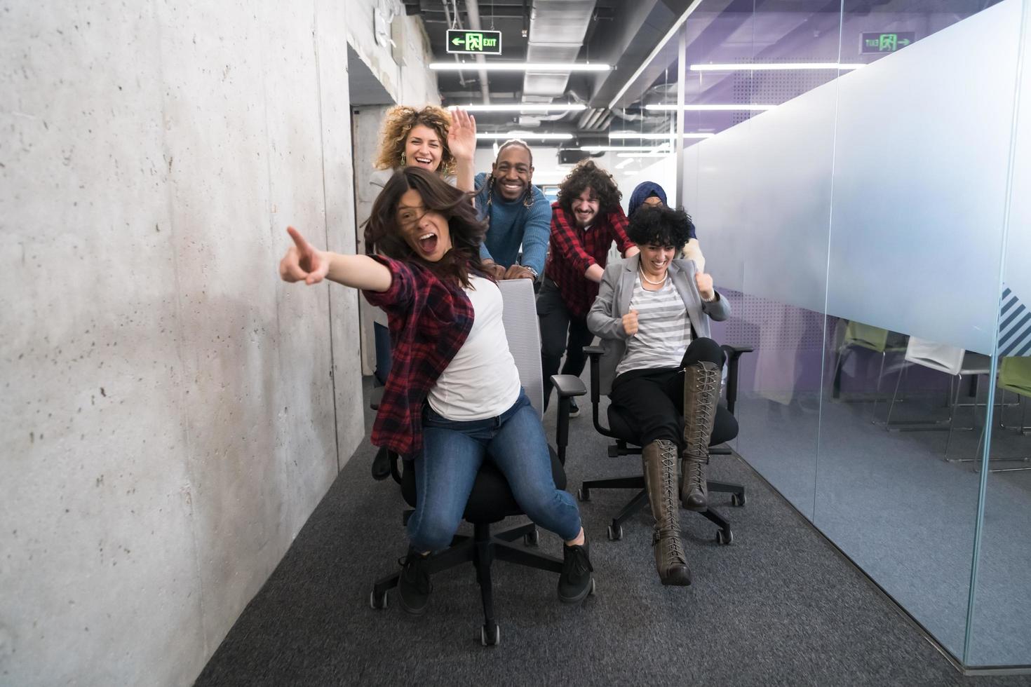 equipo de negocios multiétnico corriendo en sillas de oficina foto