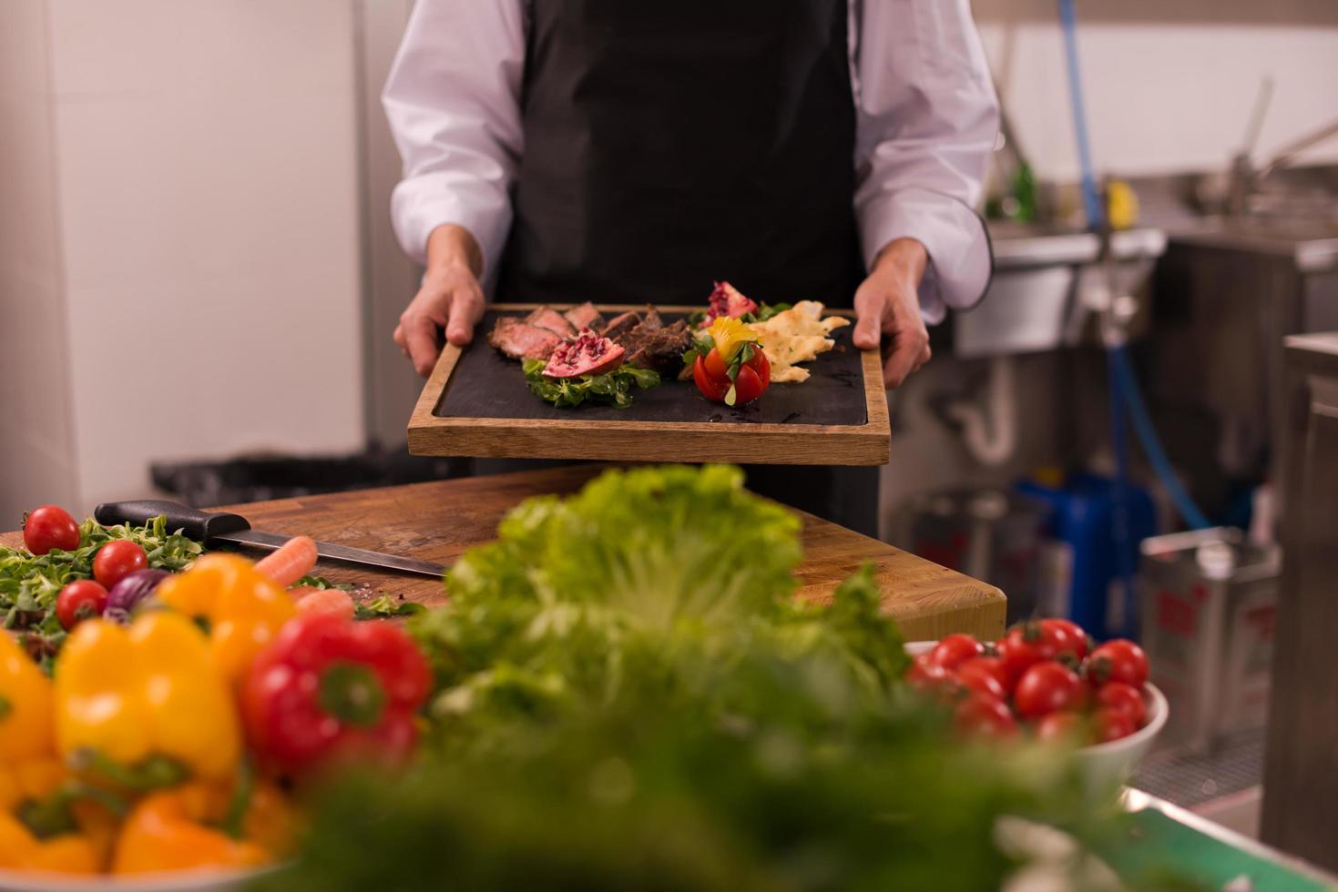 female Chef holding beef steak plate photo