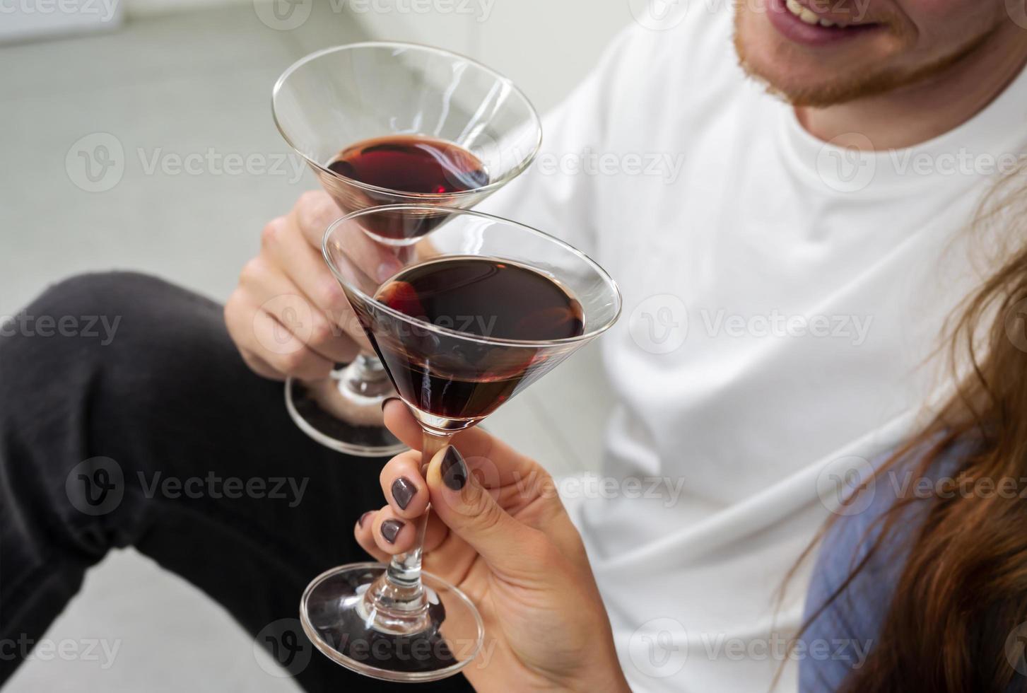 Happy man and women having fun and drinking cocktails while sitting on kitchen floor at home photo