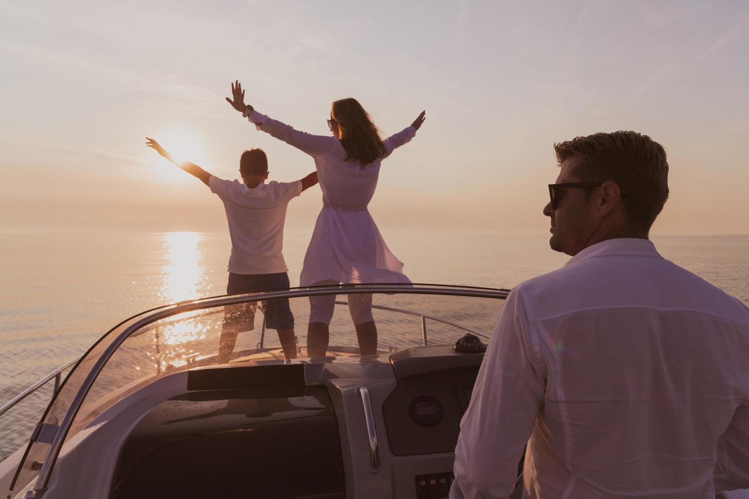 A senior couple in casual outfits with their son enjoy while riding a boat at sea at sunset. The concept of a happy family. Selective focus photo