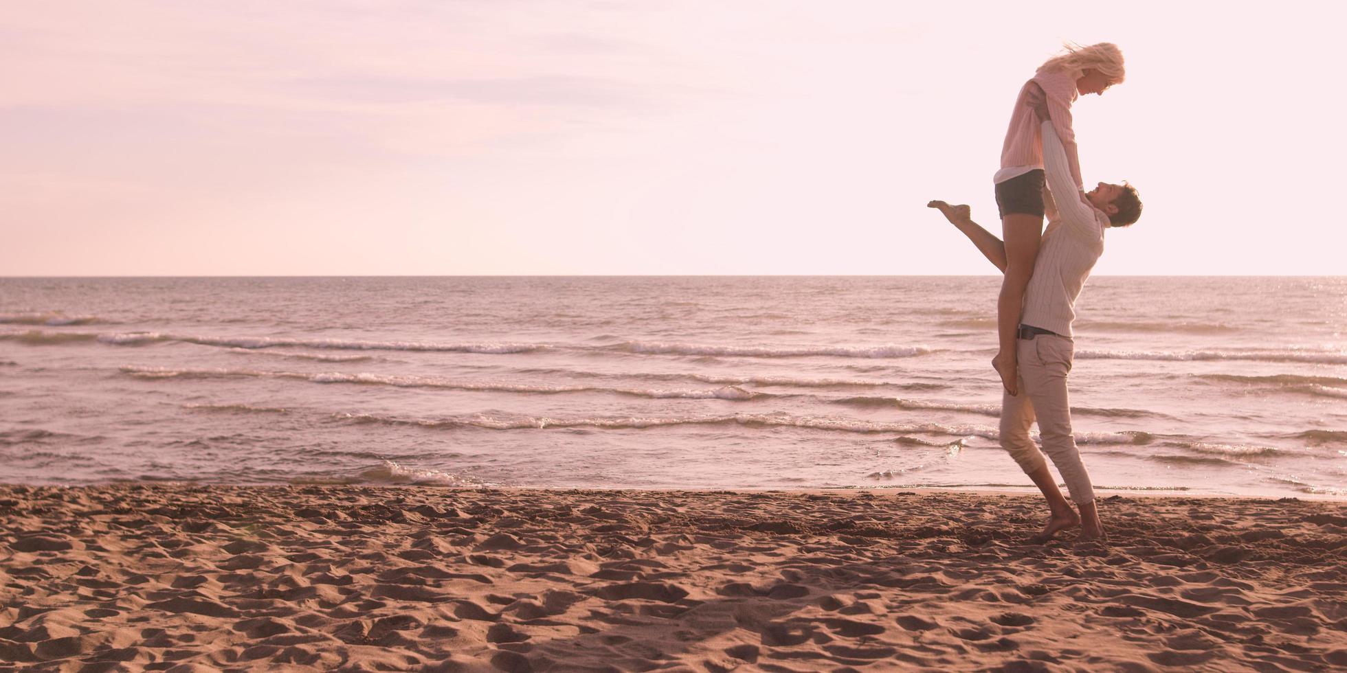 amorosa pareja joven en una playa en otoño en un día soleado foto