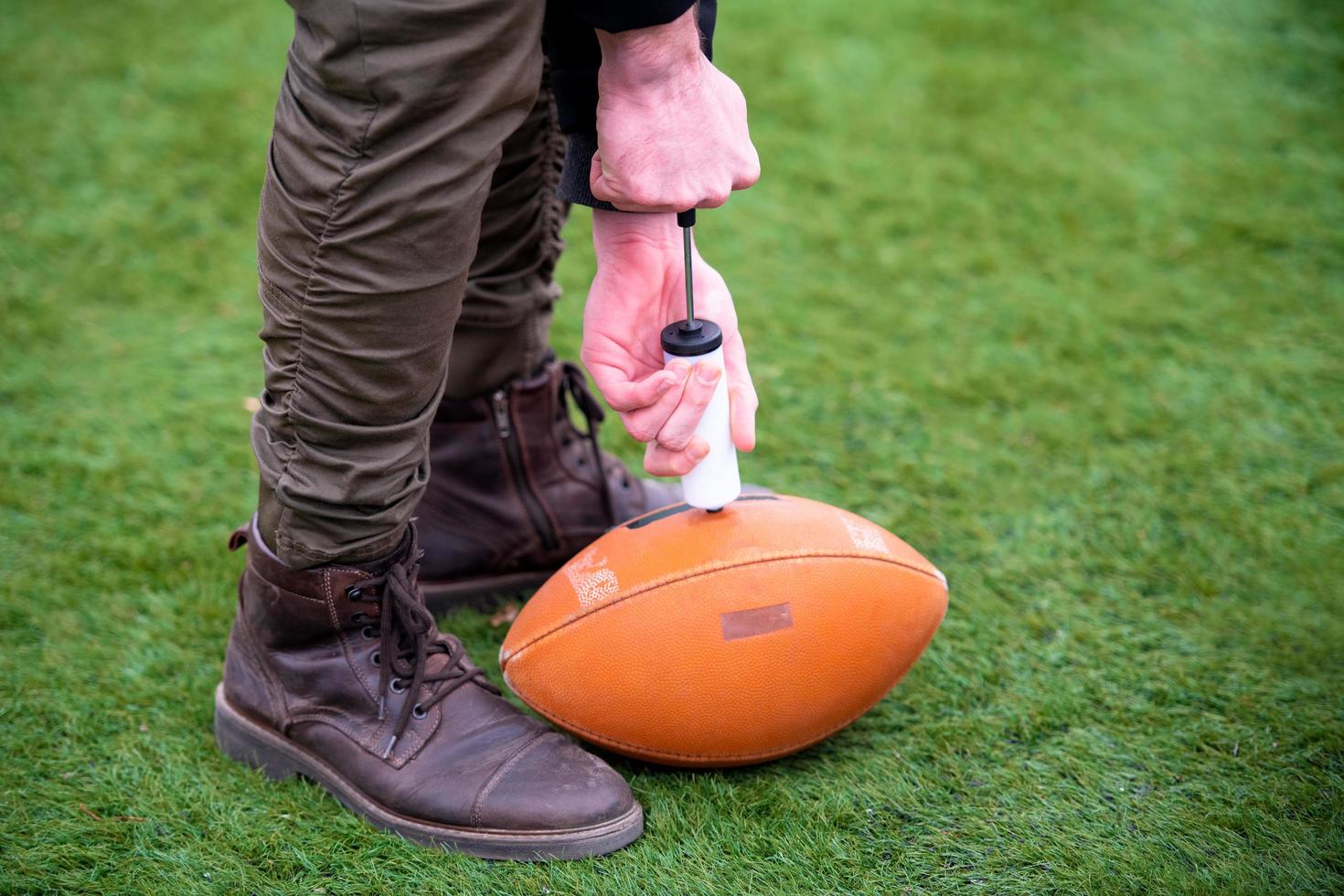 man pumping air into american football ball photo
