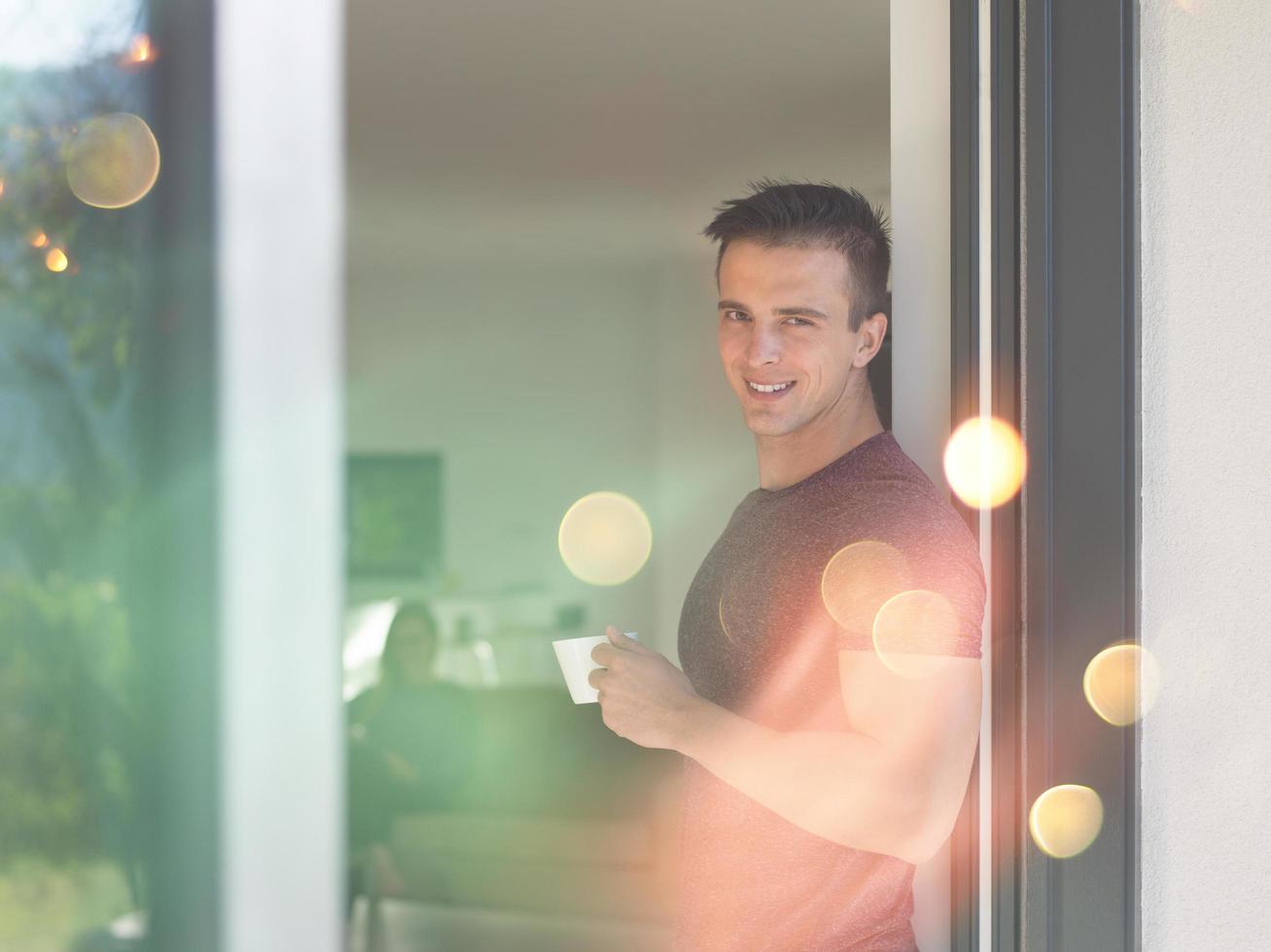 man drinking coffee in front of her luxury home villa photo