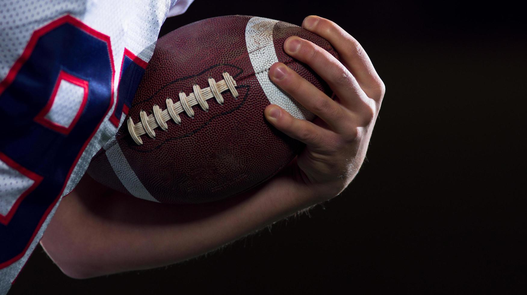 American football player holding ball while running on field photo