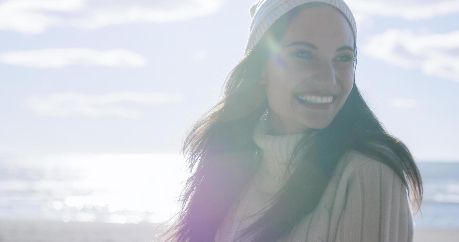 niña en ropa de otoño sonriendo en la playa foto