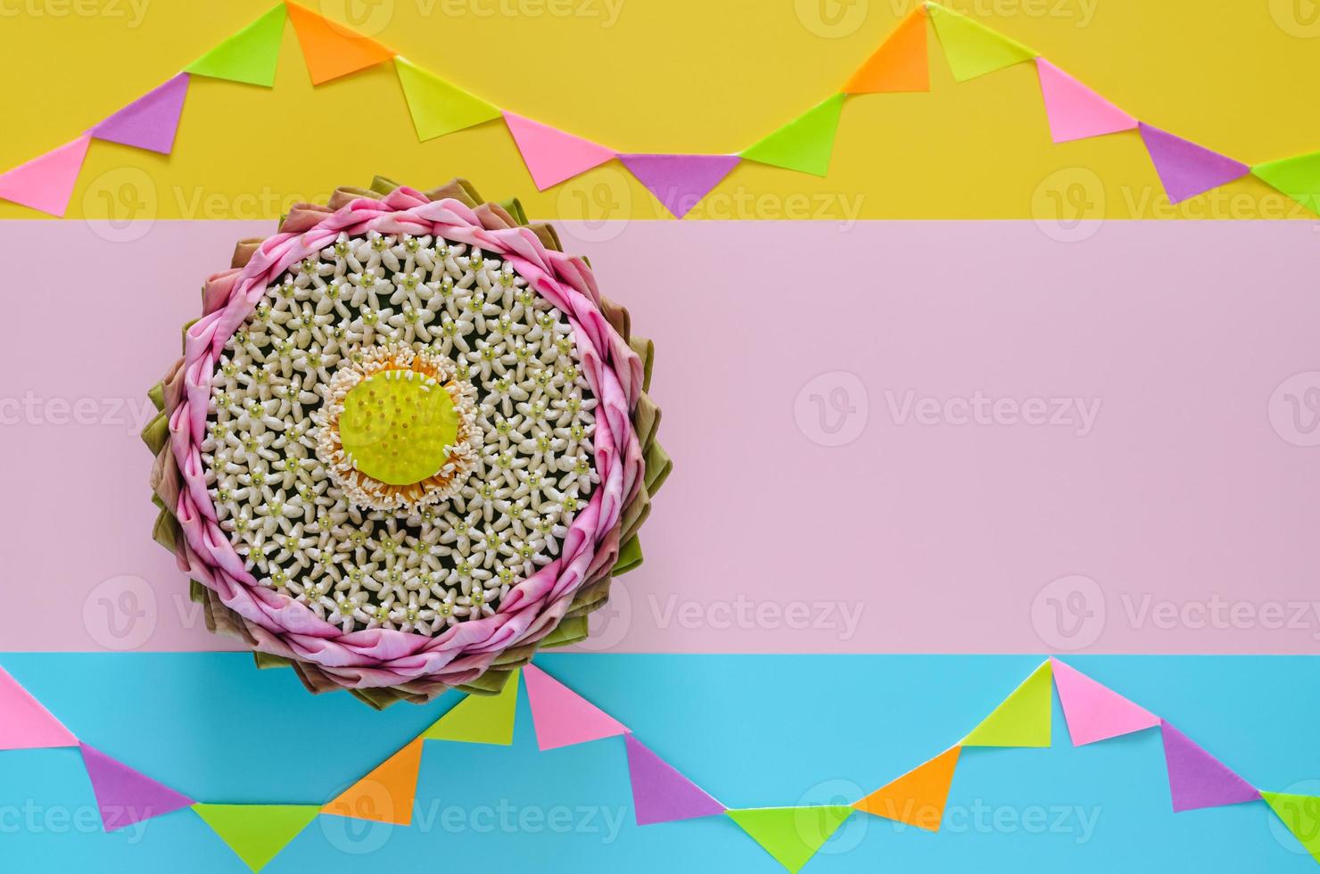 Pink lotus petal krathong decorates with its pollen and crown flower for Thailand Loy Krathong festival on colorful background with party flag. photo