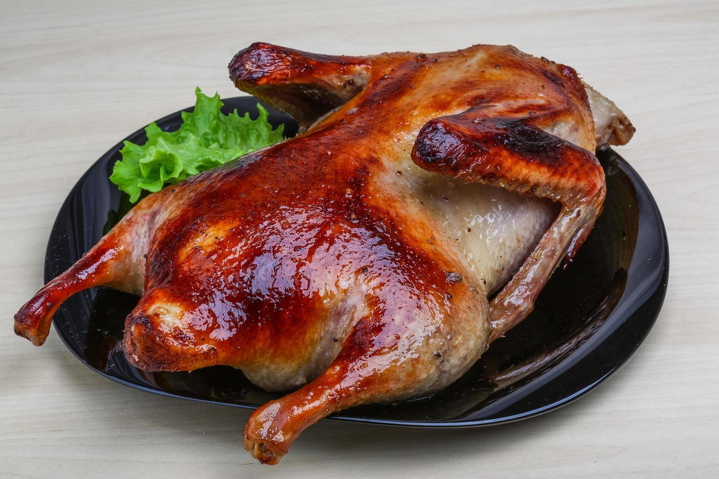 Roasted duck on the plate and wooden background photo