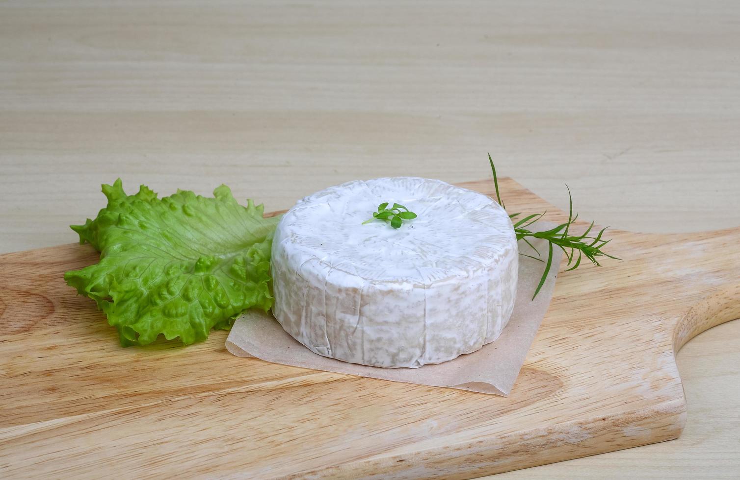 Camembert cheese on wooden board and wooden background photo