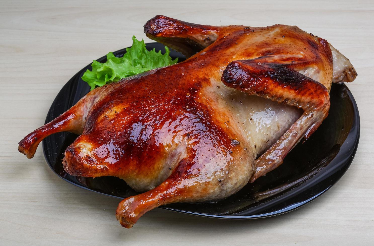 Roasted duck on the plate and wooden background photo