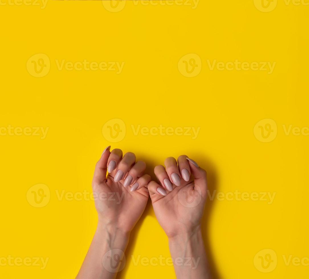 Female hands with a beautiful manicure on a yellow background,top view photo