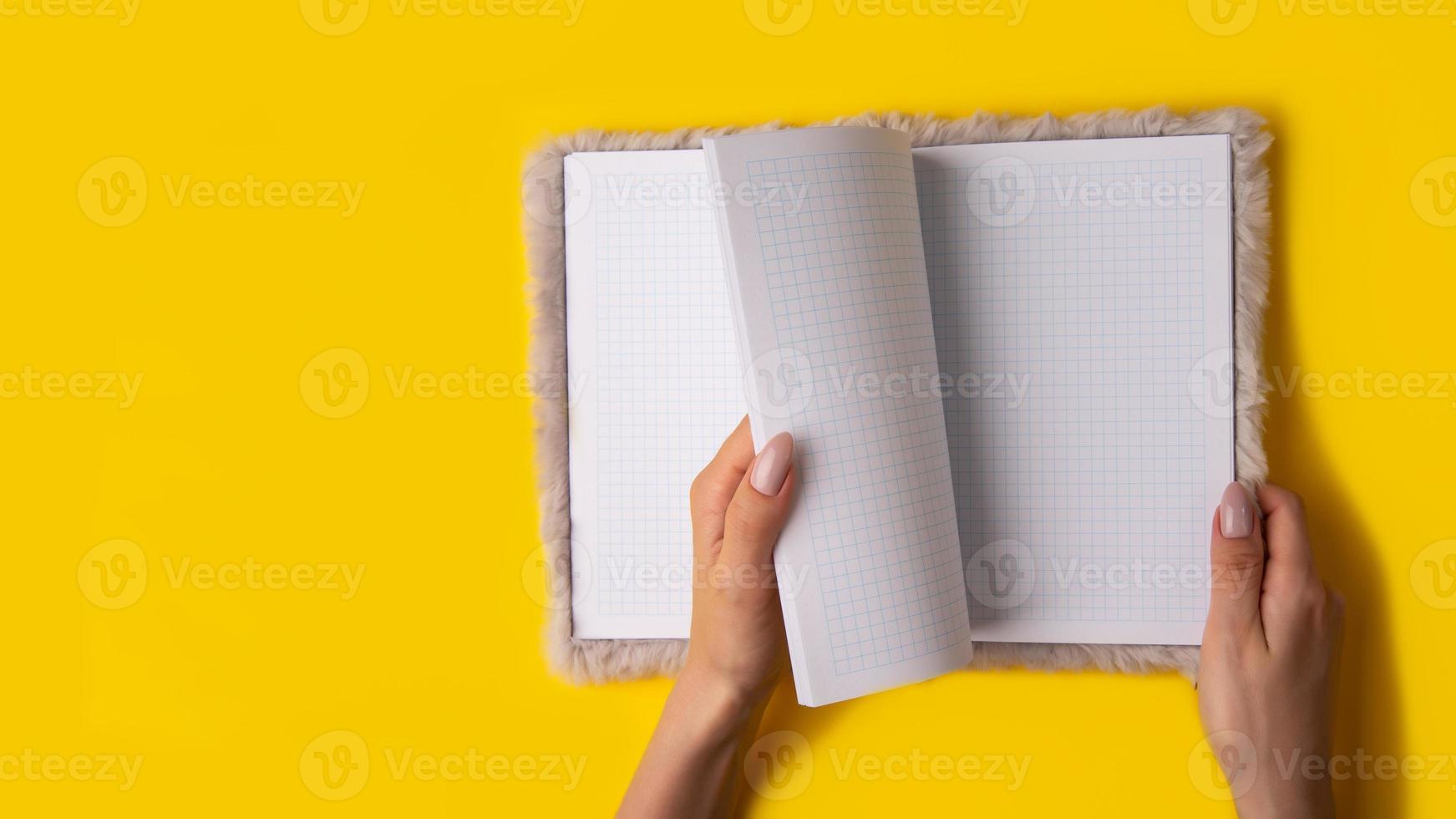 Hand hold notebook empty spread on yellow background,banner photo