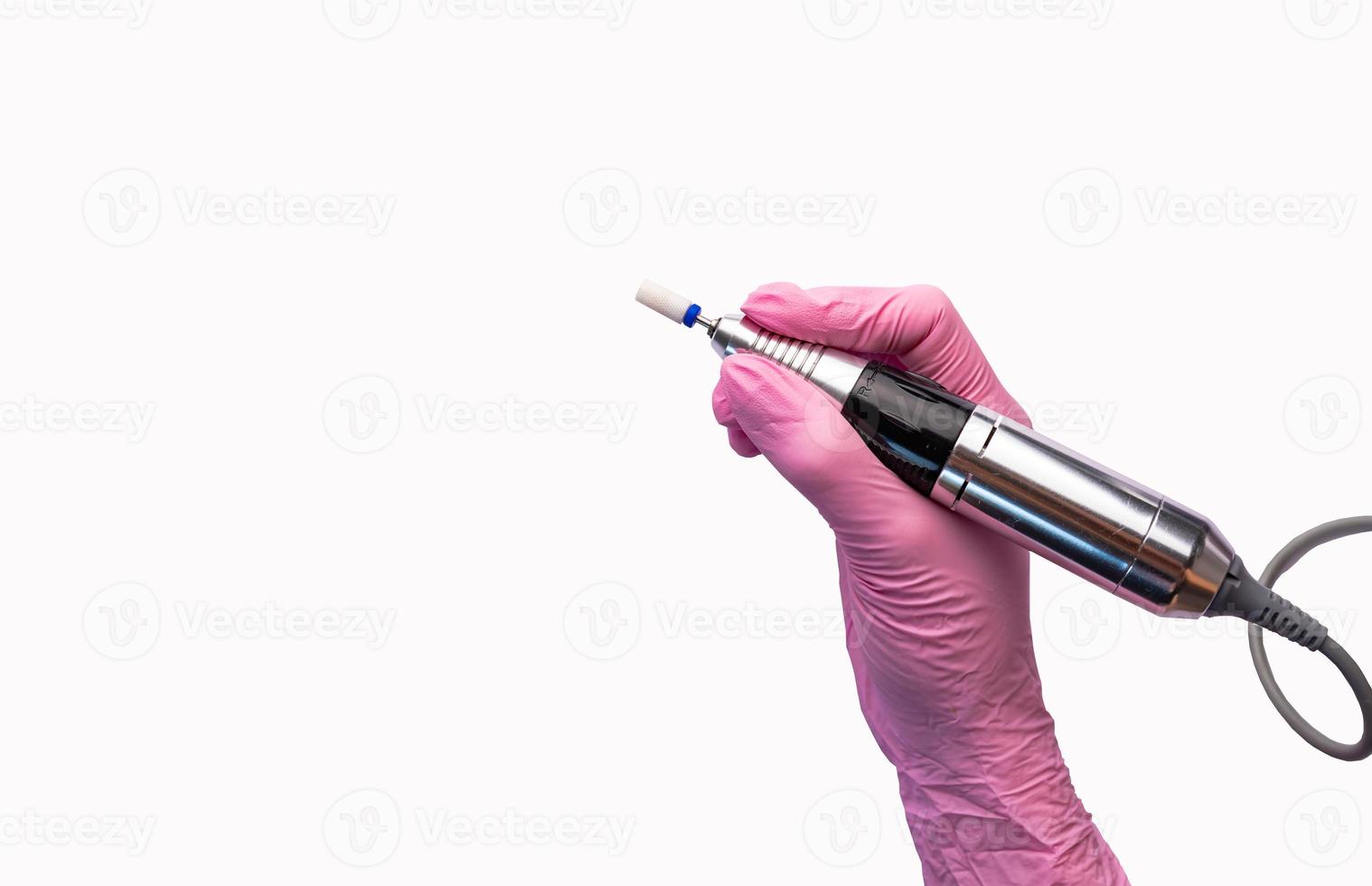 A manicurist in gloves holds a nail drill. photo