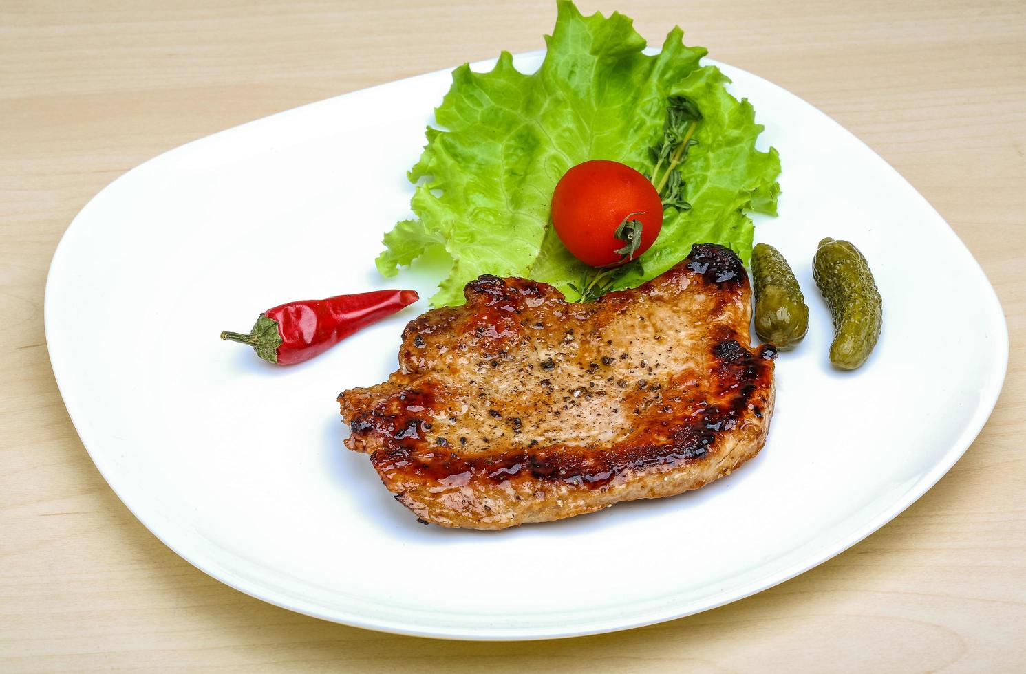 Roasted pork on the plate and wooden background photo