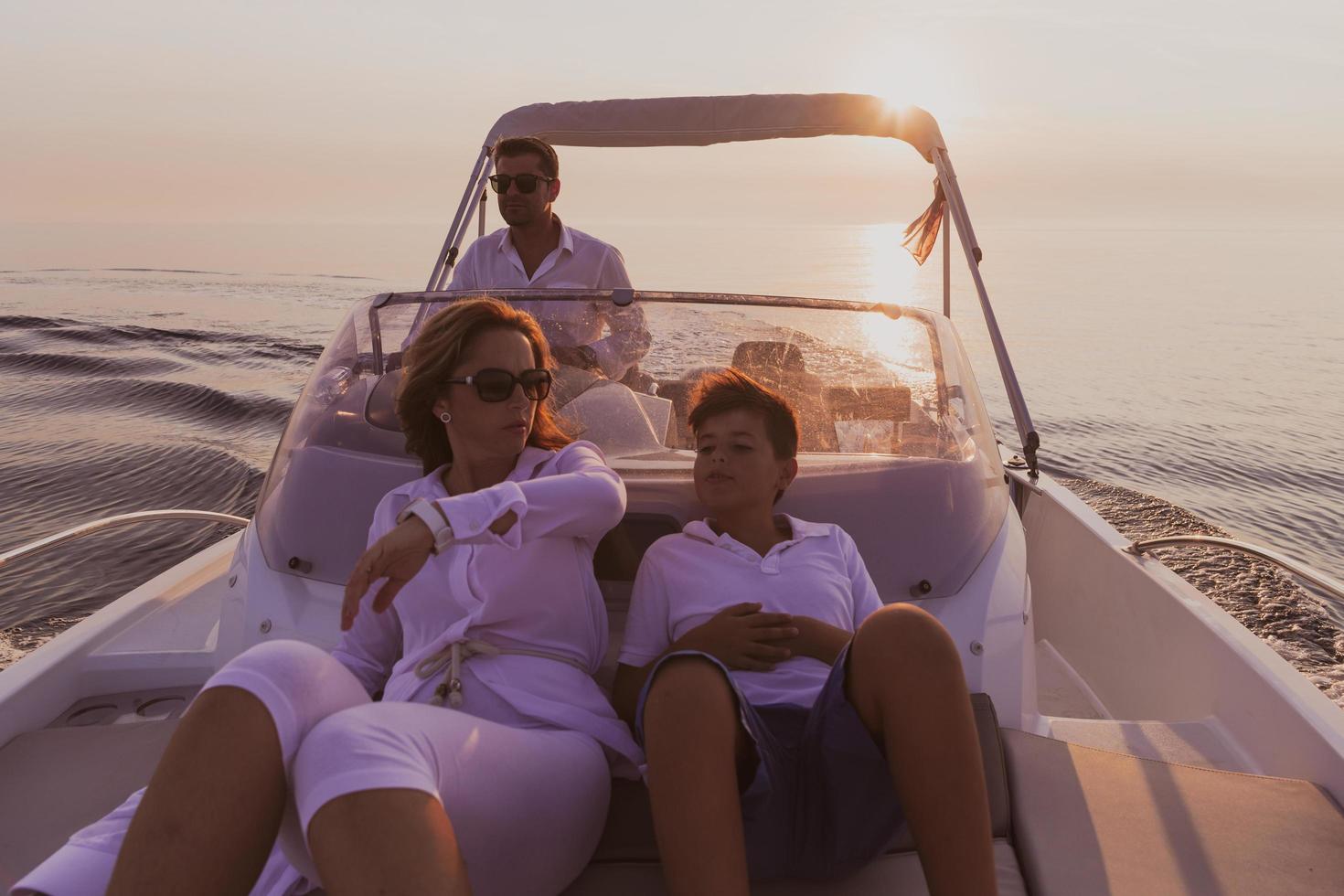 A senior couple in casual outfits with their son enjoy while riding a boat at sea at sunset. The concept of a happy family. Selective focus photo