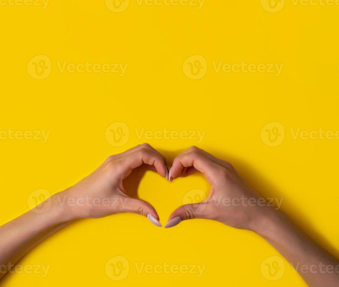 heart making woman's hands with manicure on yellow background, top view,banner photo