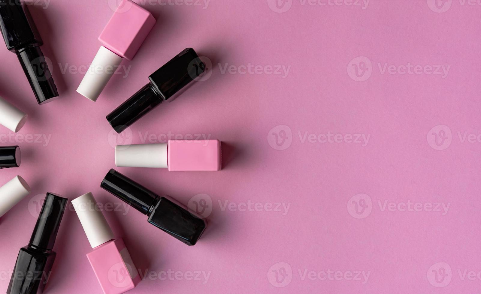 Set of vials with colorful nail lacquer placed in circle on pink background photo