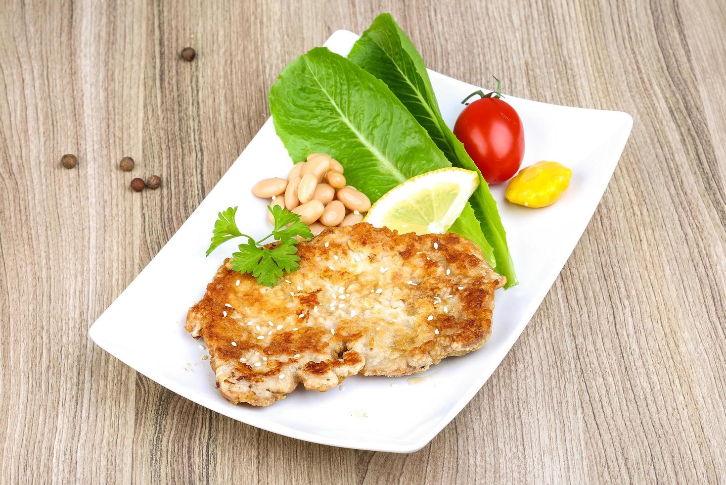 Pork schnitzel on the plate and wooden background photo