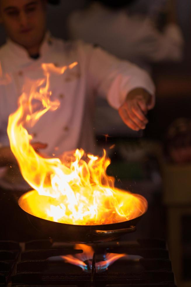 chef haciendo flambeado en la comida foto