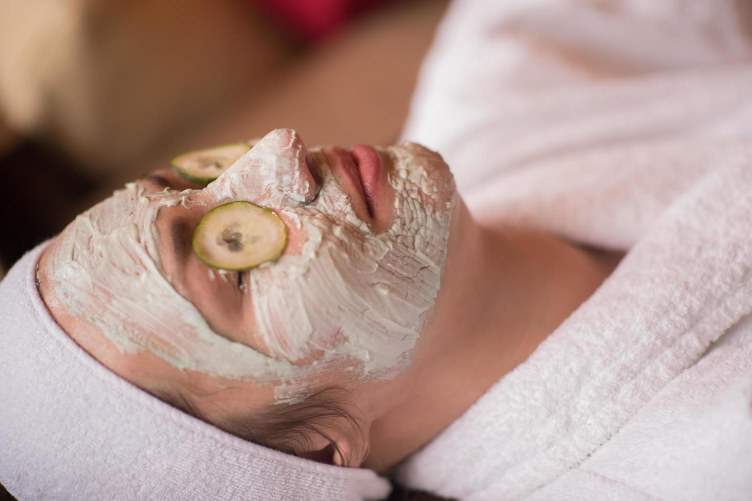 woman is getting facial clay mask at spa photo